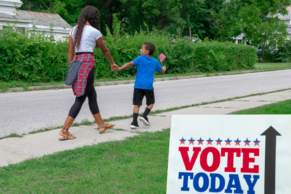 An excited son tugs at his mother's arm to vote on Election Day.